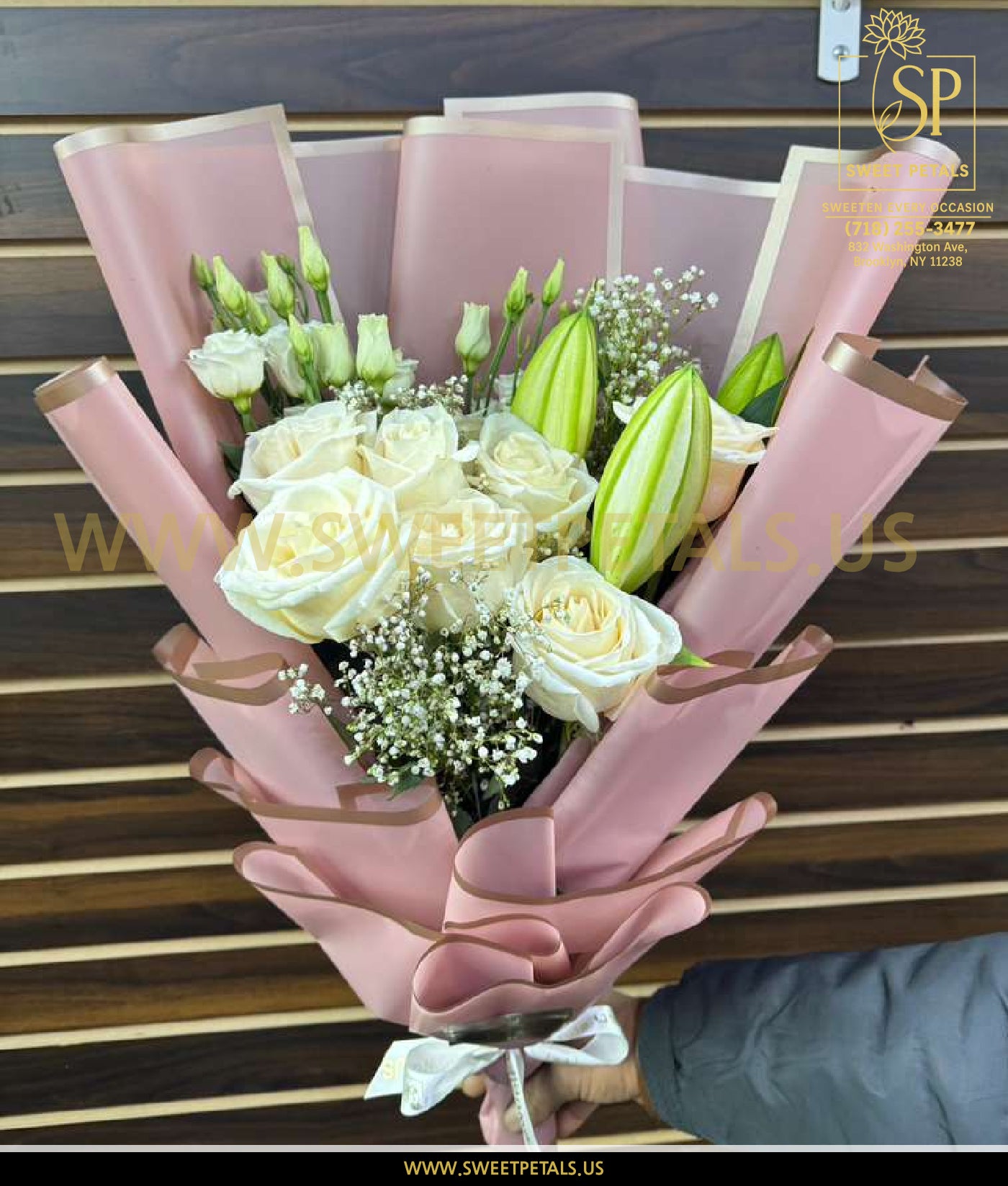 White rose and lily bouquet with large white roses, fresh greenery, and lily buds wrapped in soft pink paper for an elegant floral arrangement.