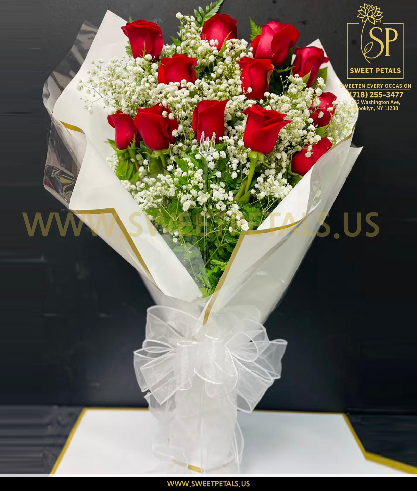 Bouquet of roses for Valentine’s Day featuring in it valentines roses arranged with white baby’s breath and greenery, an elegant bouquet Valentine’s Day flowers wrapped in white paper with a sheer ribbon.