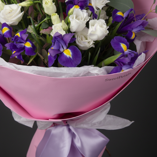 Close-up of deep purple iris and white lisianthus blooms in pink wrapped bouquet – SweetPetals luxury flowers