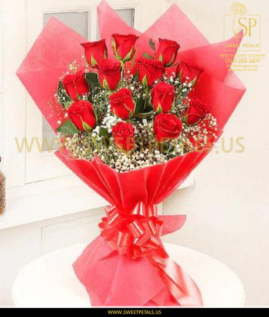 Elegant bouquet of fresh red roses with white baby’s breath, wrapped in red floral paper and tied with a matching ribbon, perfect for romantic occasions.