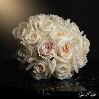 Close-up of creamy white O'Hara garden roses with one blush center rose in dome bouquet on dark marble – SweetPetals white garden rose luxury bridal bouquet