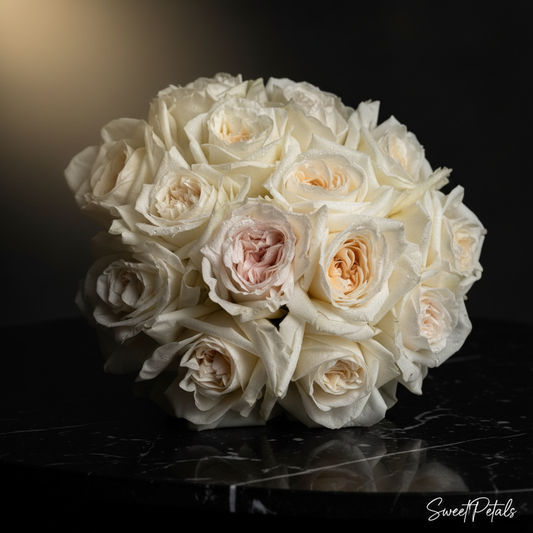 Close-up of creamy white O'Hara garden roses with one blush center rose in dome bouquet on dark marble – SweetPetals white garden rose luxury bridal bouquet