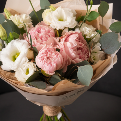 Close-up of blush pink peonies and white lisianthus with eucalyptus in cream wrap – SweetPetals luxury peony bouquet